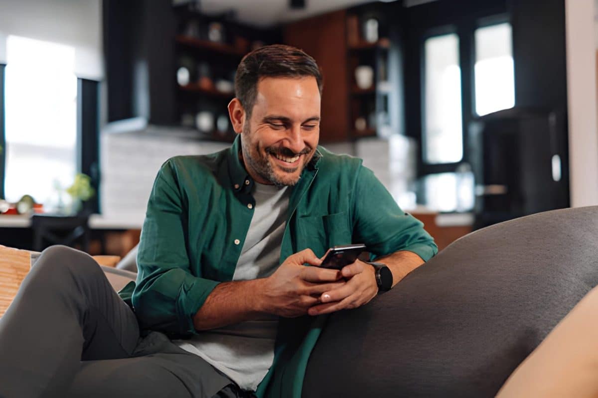 Man relaxing on the sofa using his smartphone