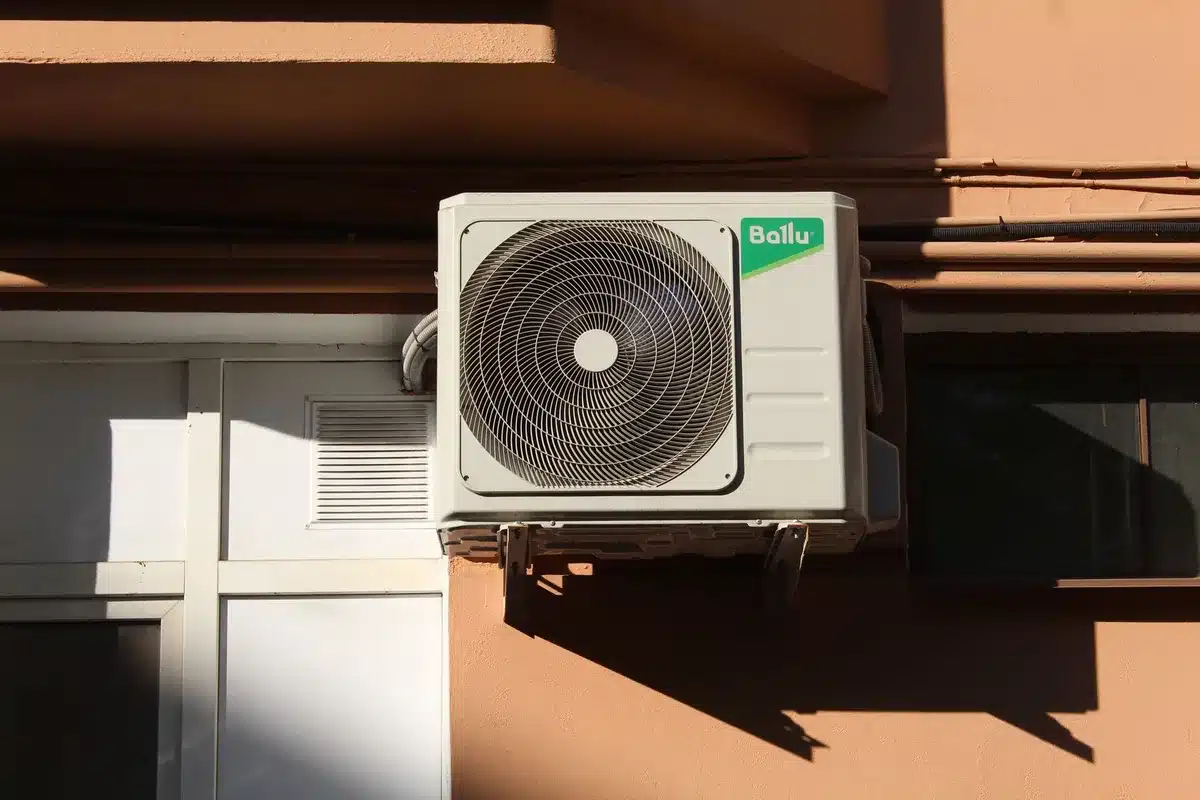 Outdoor AC condenser unit with debris and leaves around the base