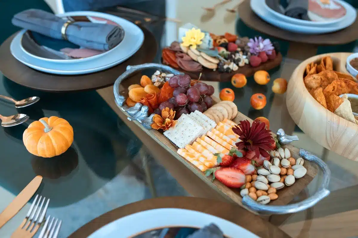 Pumpkin-shaped wooden cutting board styled with fall cheeses and charcuterie