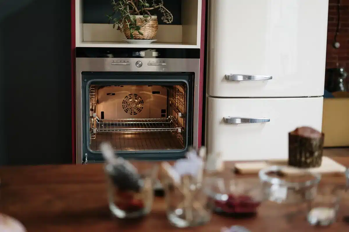 Open box of baking soda on a refrigerator shelf next to fresh vegetables and produce