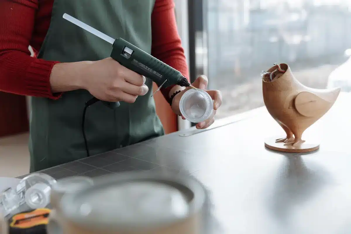 Hot glue gun applying magnet discs to clear organizer holder