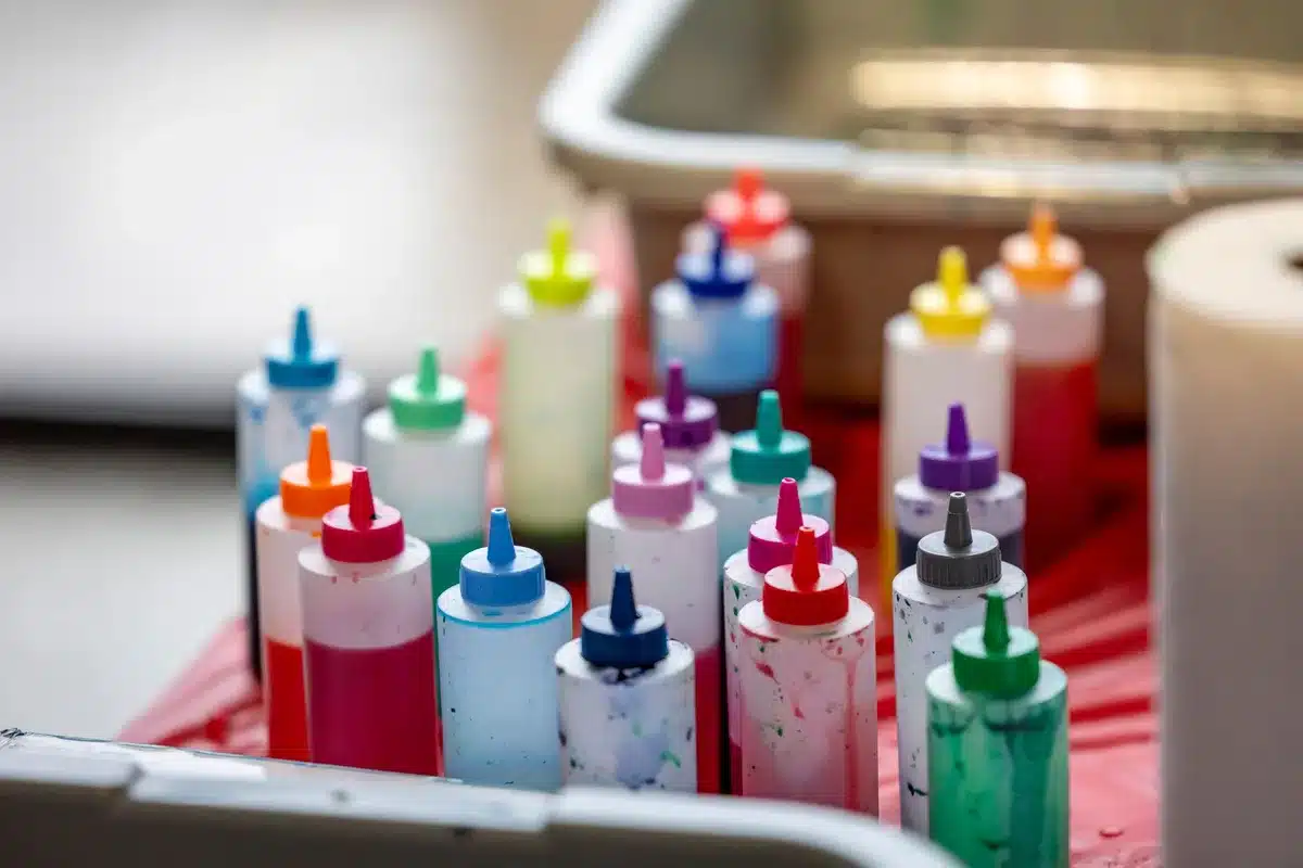 Colorful bottle caps arranged and decorated with paint and patterned paper for DIY wall art