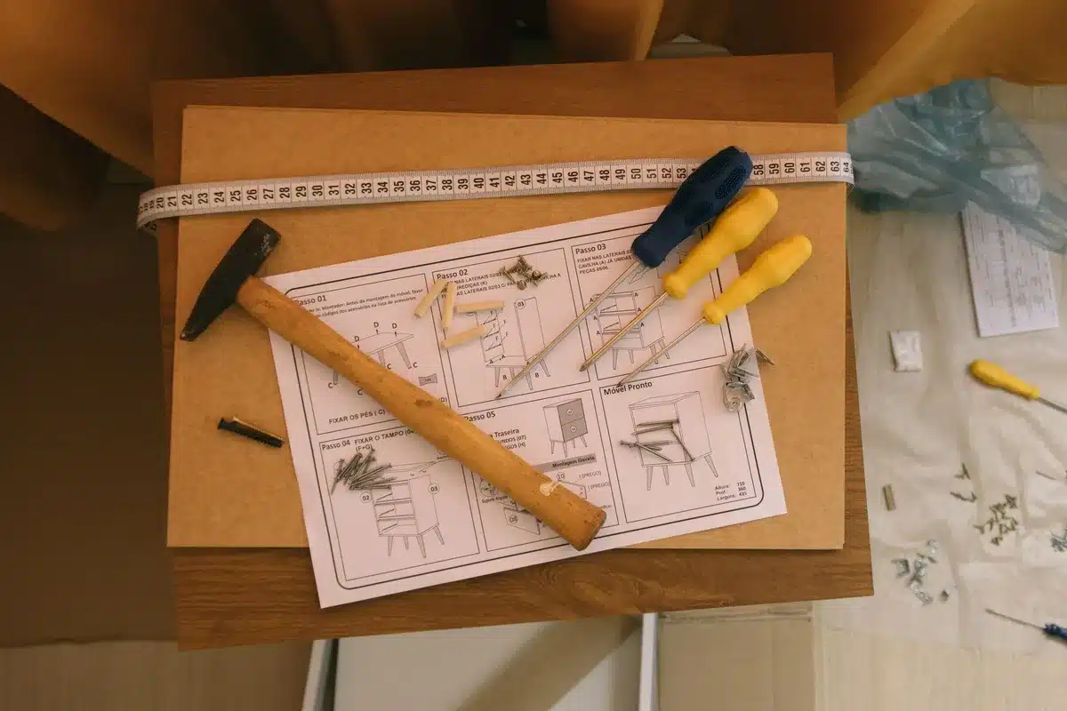Hands assembling a DIY paper towel holder with wooden frames and decorative seasonal items on a kitchen counter