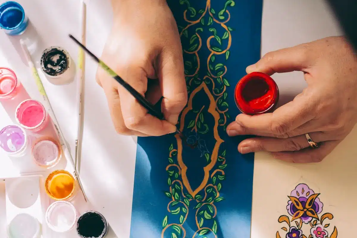 Handmade miniature vases decorated with paint and flowers arranged on a shelf