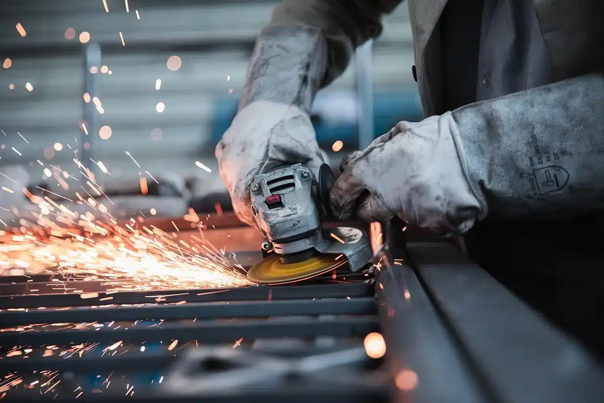 Person wearing protective gloves preparing a garden tool for sharpening