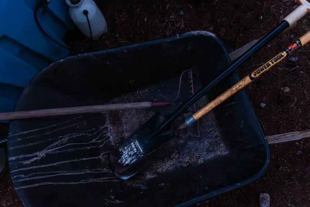 Handheld gravel tools including metal rake and hand tamper for small driveway repairs
