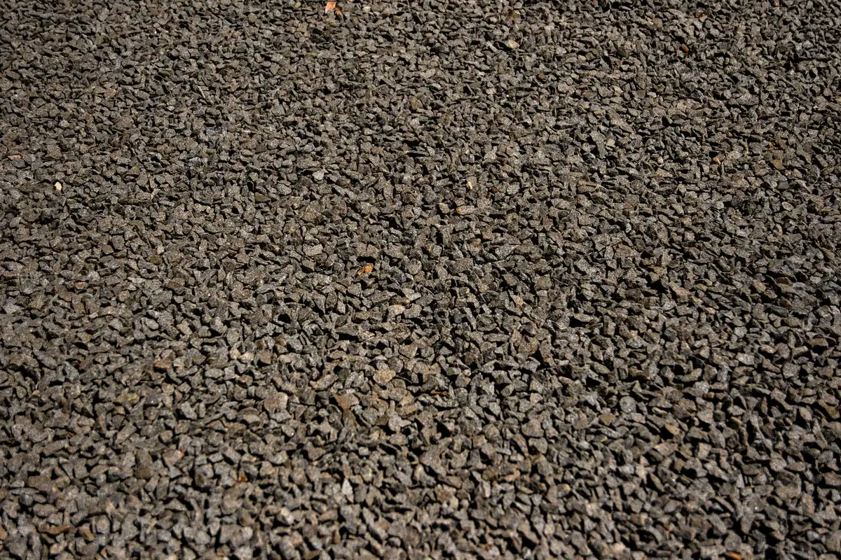 Glistening dark asphalt driveway with uniform finish and vehicle