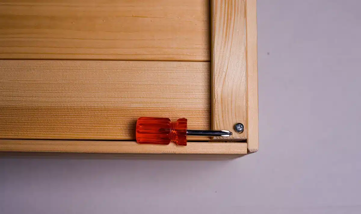 Hands assembling wooden pallet boards into a storage box frame on a workshop table