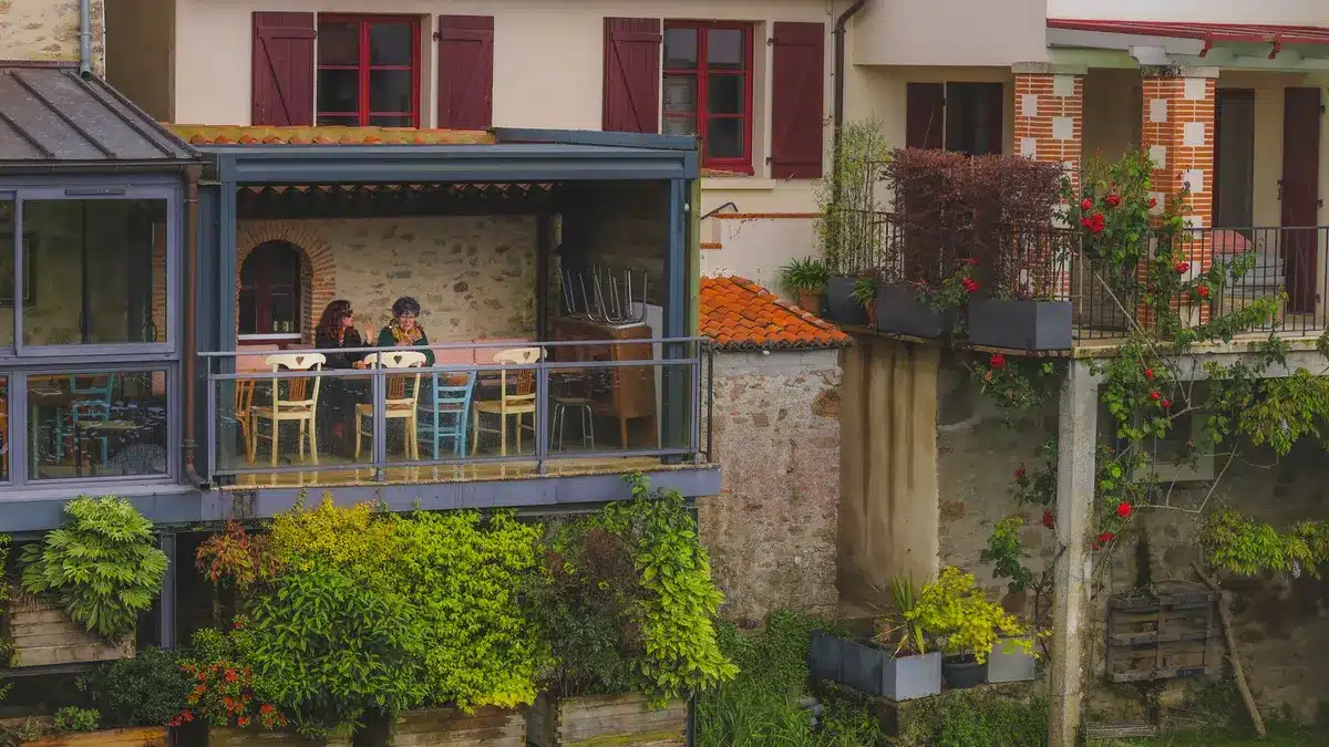 Two people enjoying a meal on a compact wooden bistro set on a small balcony