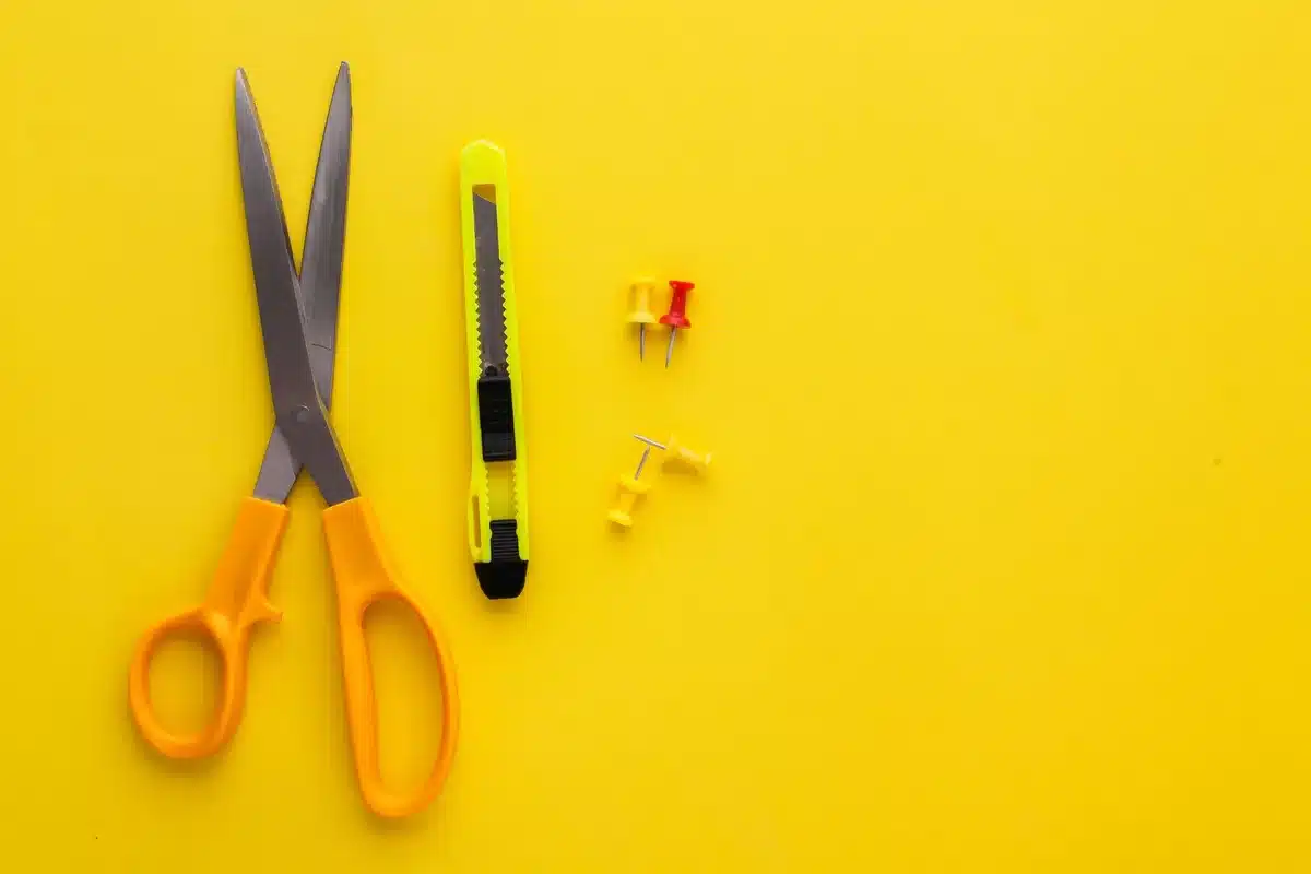 Basic DIY tools including scissors, utility knife, and adhesive hooks laid out on a surface