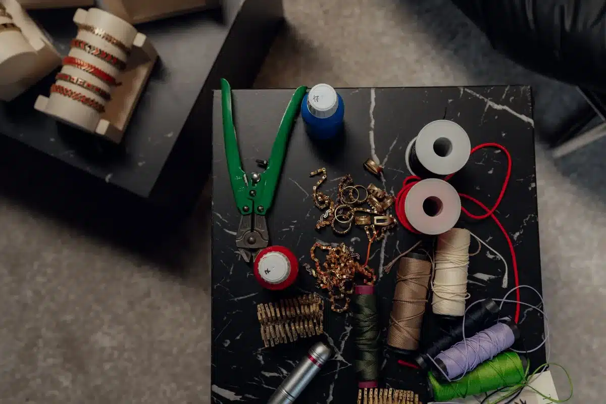DIY craft supplies including beads, wire, pliers, and a metal whisk laid out on a workspace