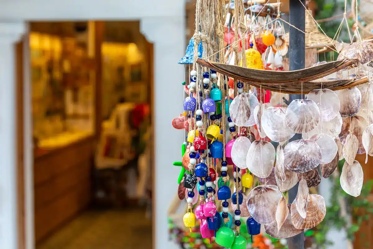 Homemade seashell wind chime with shells threaded on cord hanging from driftwood