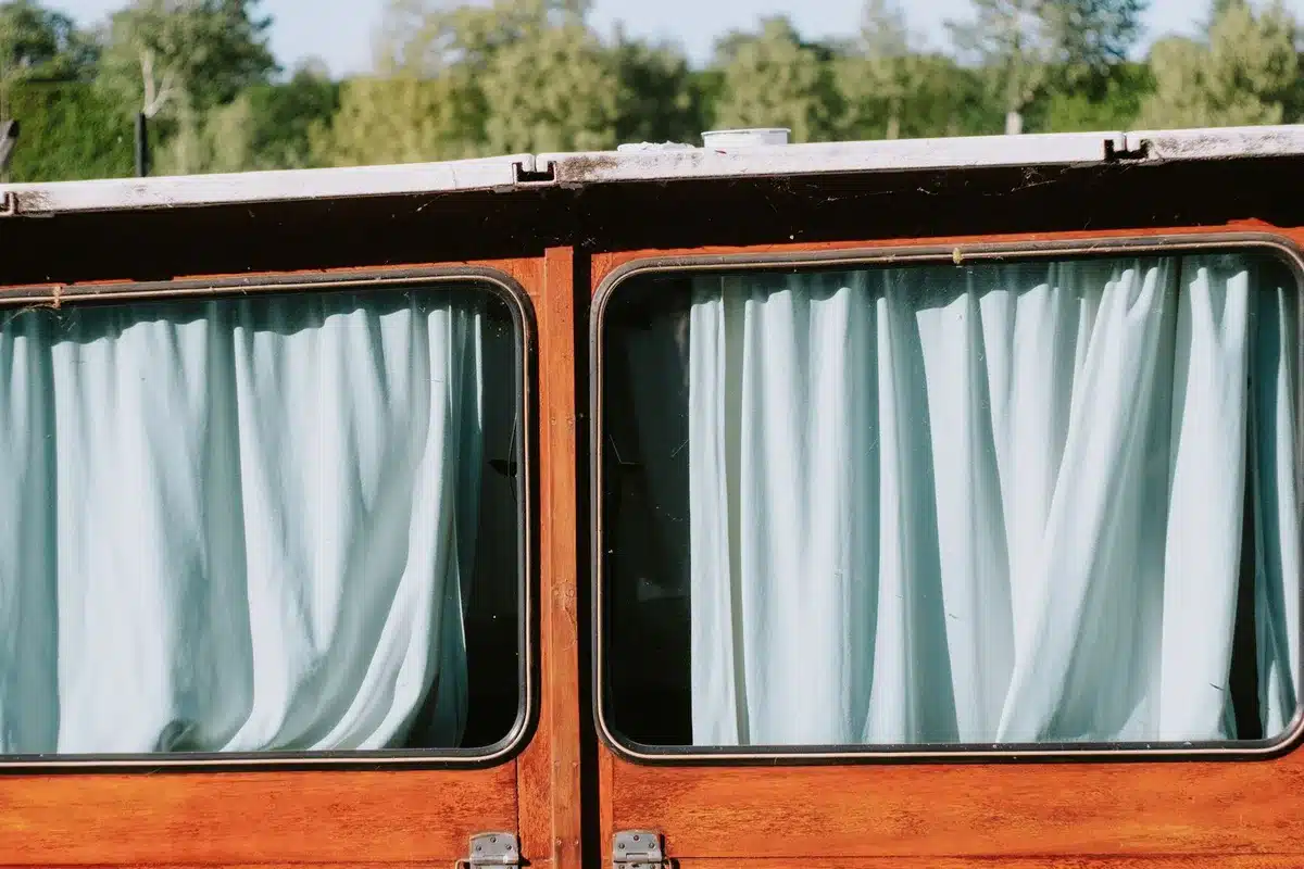 Vintage flour-sack fabric draped as window covering, showing printed textile design and soft natural light filtering thr