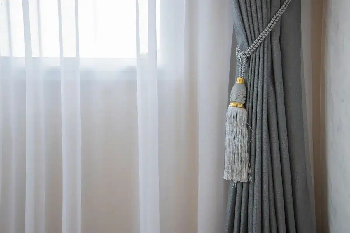 Layered window treatment combining sheer vertical blinds with Roman shade and heavy curtains for versatile light and pri
