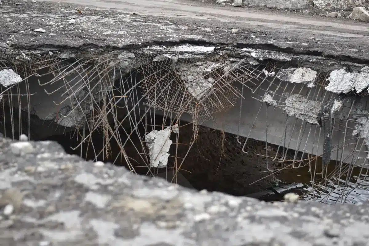 Wire brush and scraper clearing dirt and debris from a pavement crack