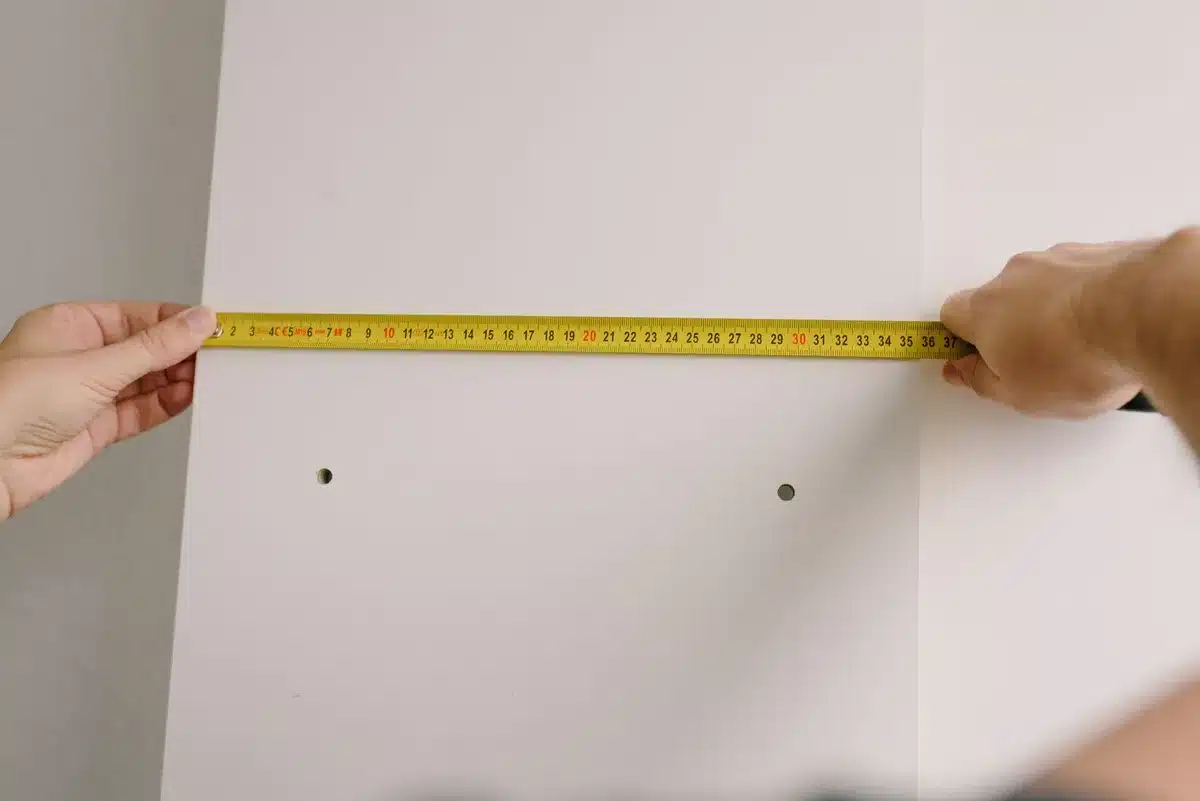 Measuring bathroom space with tape measure before buying storage