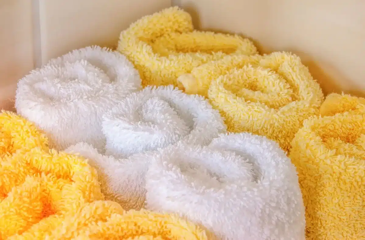 Rolled towels stacked neatly on bathroom storage shelves