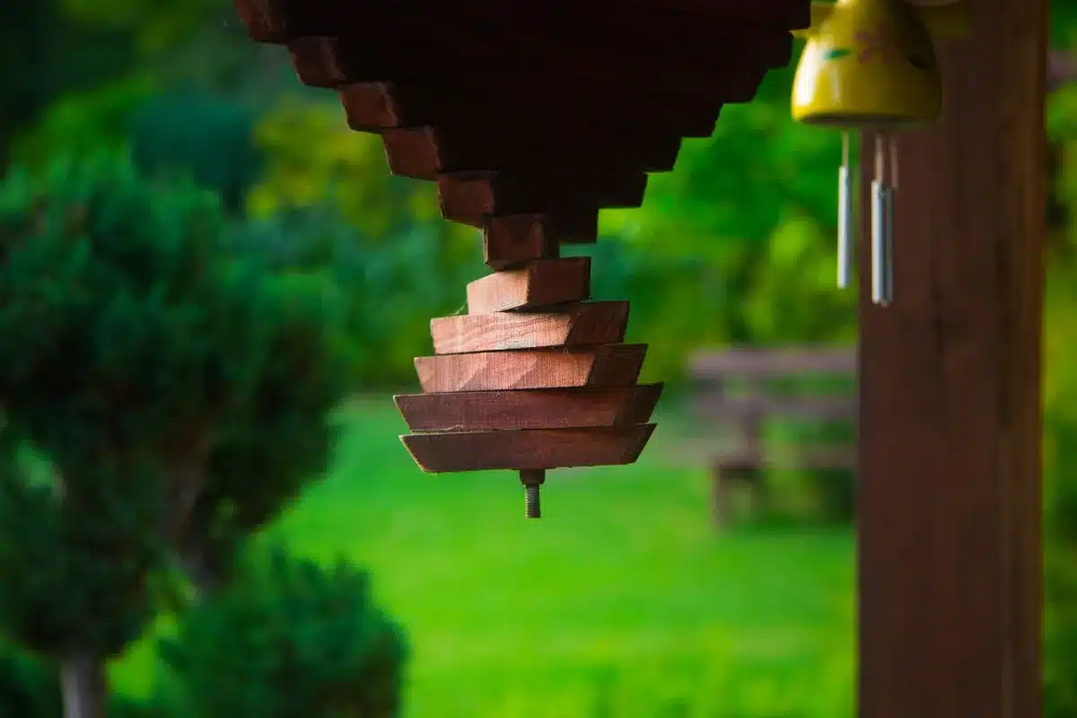 Hängende Teeschalen mit Perlen und Muscheln an Holzrahmen in Gartenumgebung