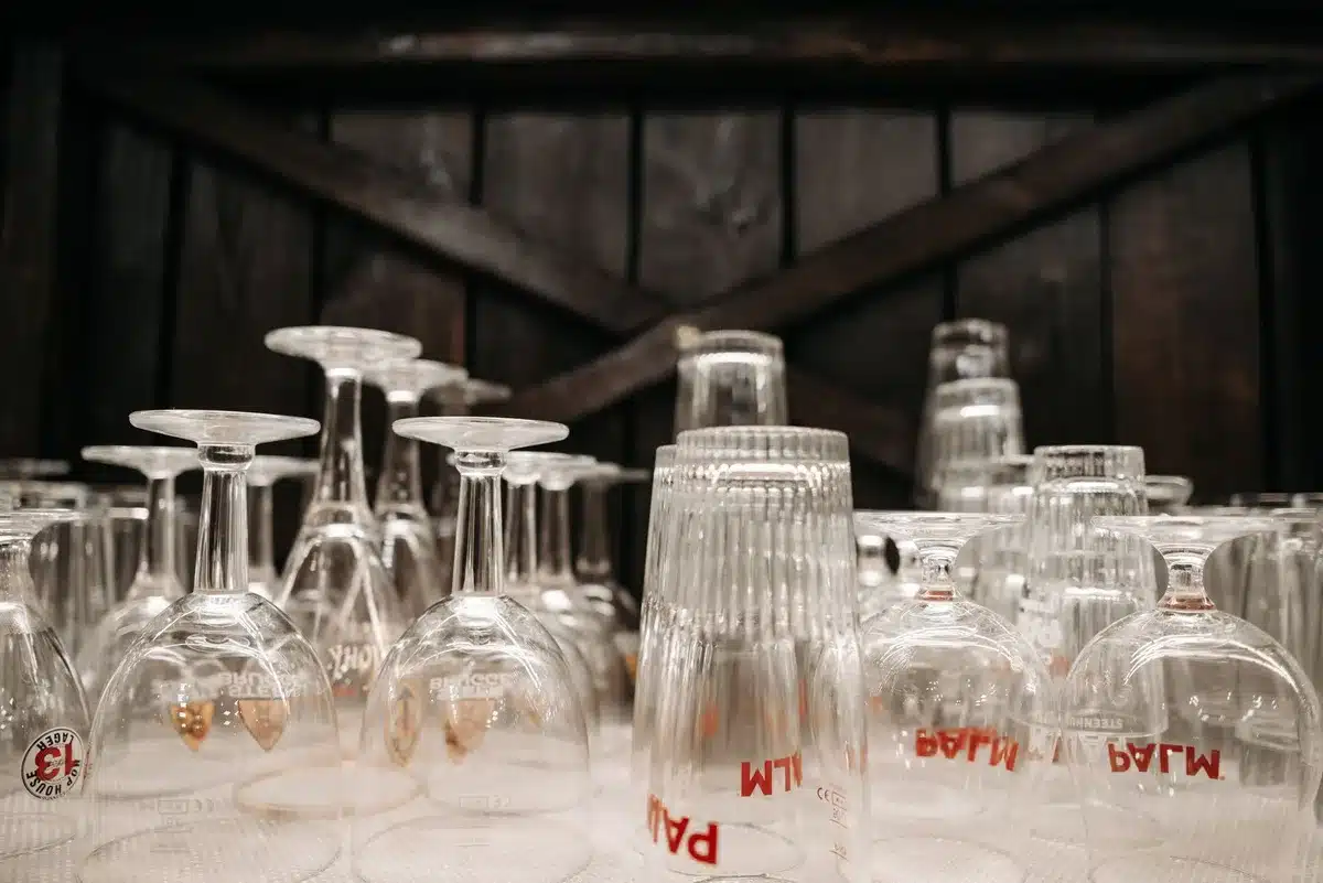 Vintage geometric-patterned glass tumbler held carefully in a thrift shop setting with warm lighting