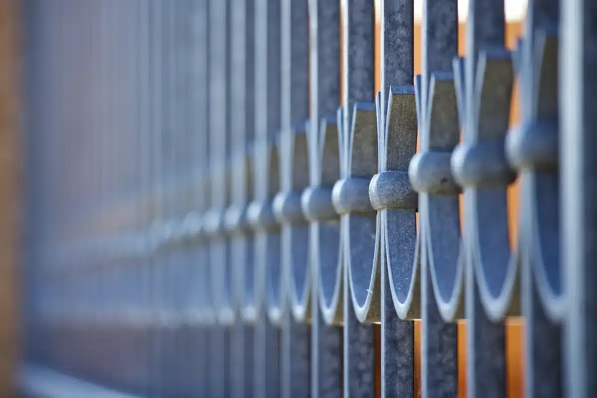 Hands threading zip ties through grommets to attach a privacy screen to a balcony railing