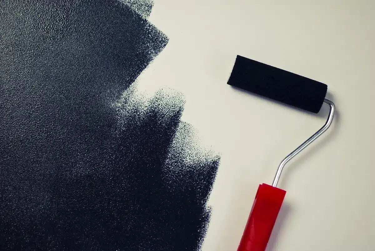 Roller applying thick ceiling paint to textured ceiling