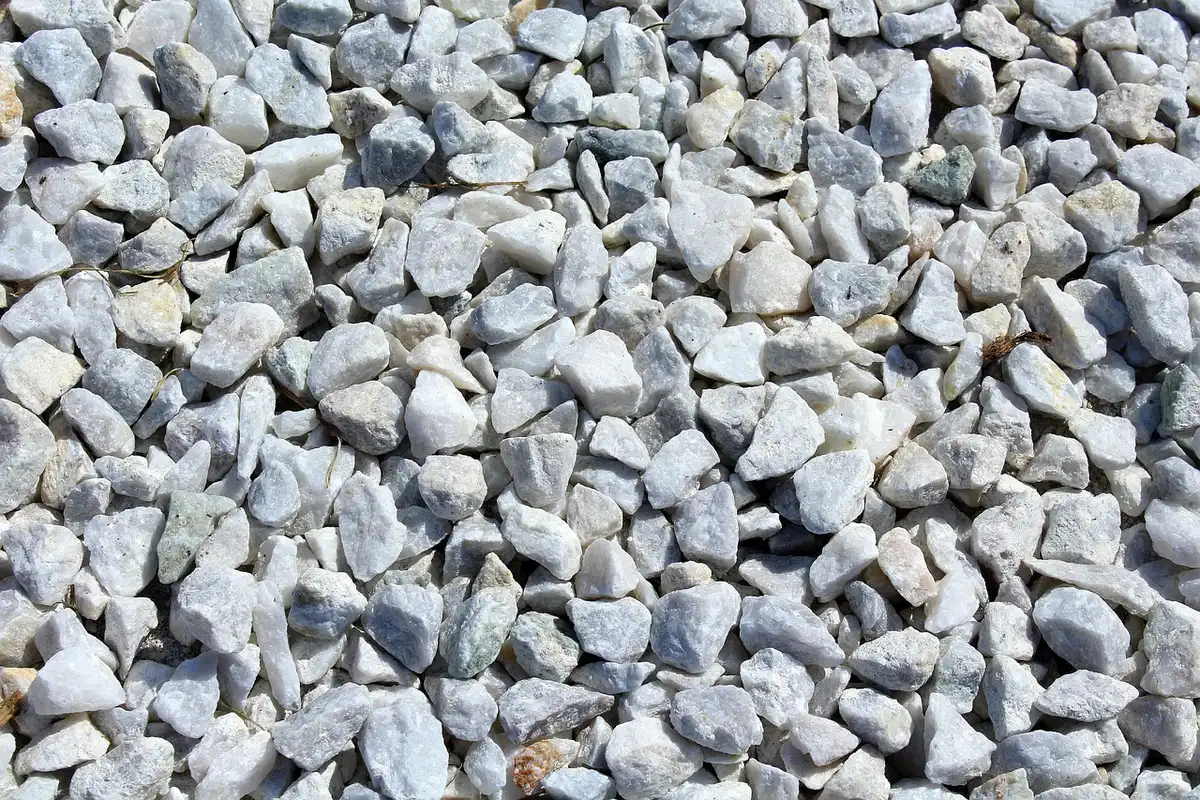 Close-up of hands holding mixed crushed and rounded gravel by a suburban driveway in daylight