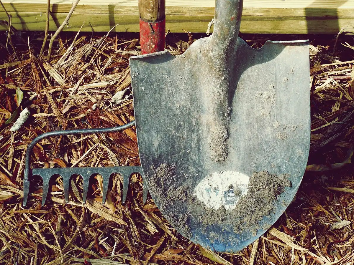 Rake spreading topsoil evenly into a lawn depression