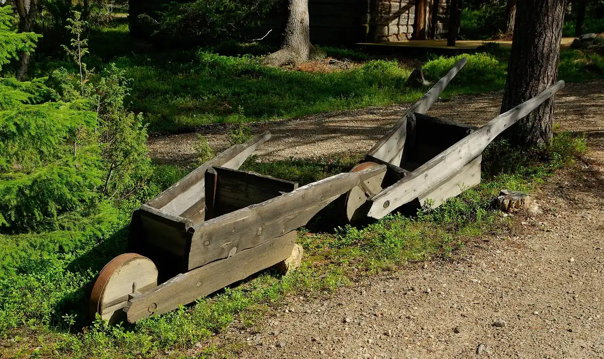 Wheelbarrow, heavy-duty gloves and a tarp leaning beside a garden bed