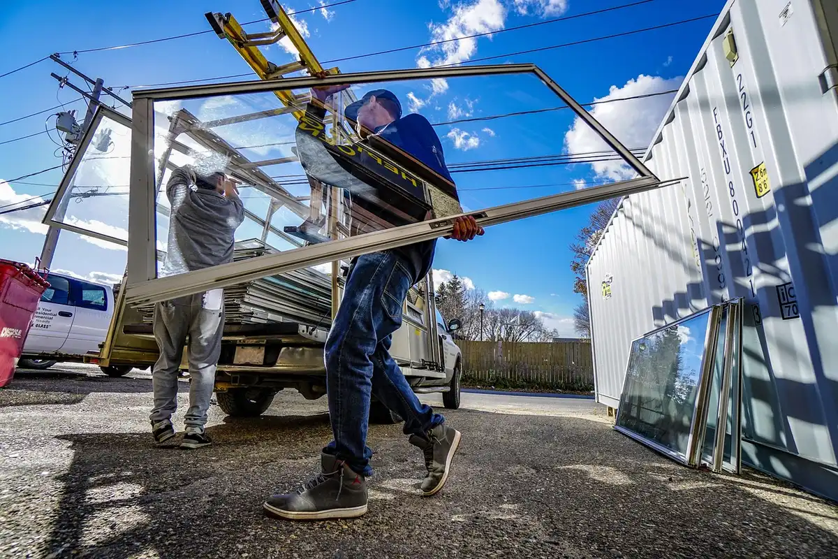 Hands applying frosted window film to glass with a squeegee and spray bottle