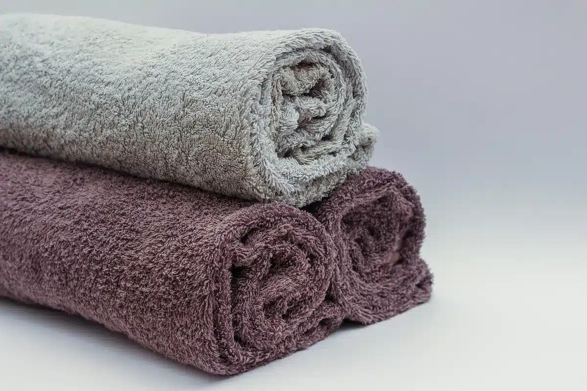 Neatly folded towels grouped by size on a shelf inside a cabinet