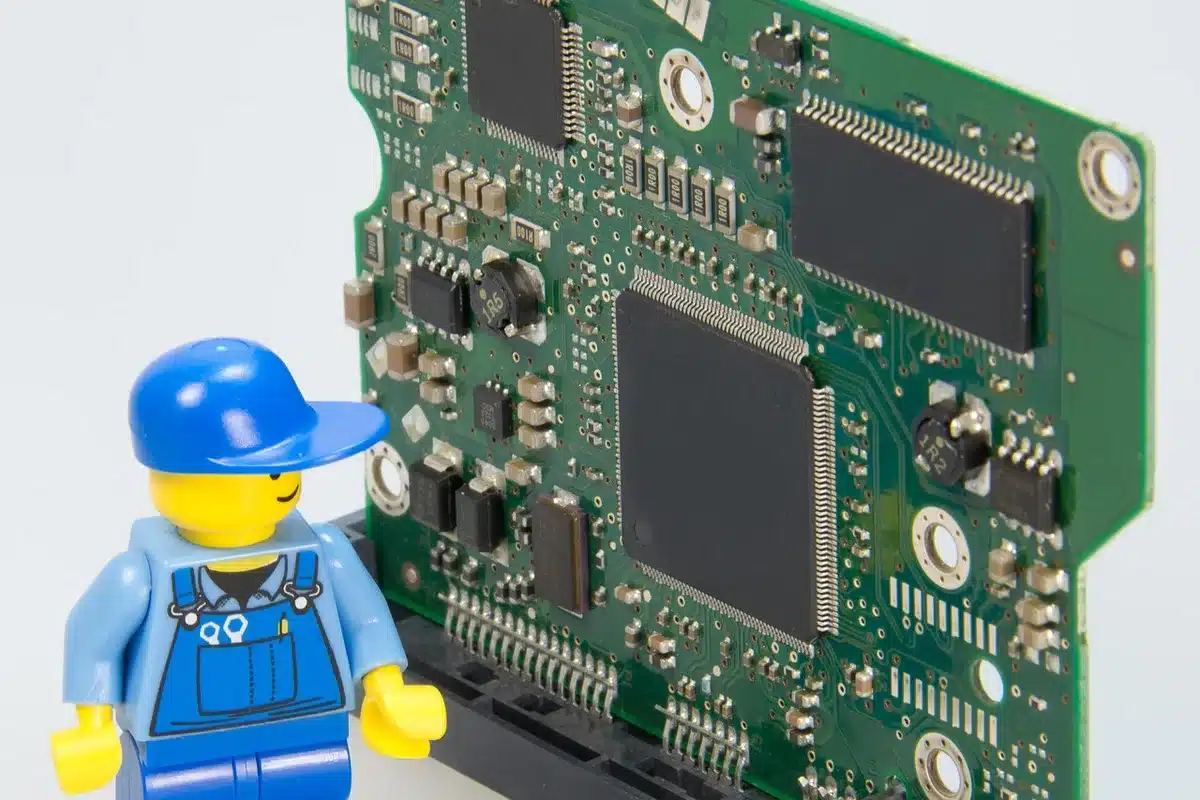 Close-up of a circuit board and a small aerosol can on a bright workbench