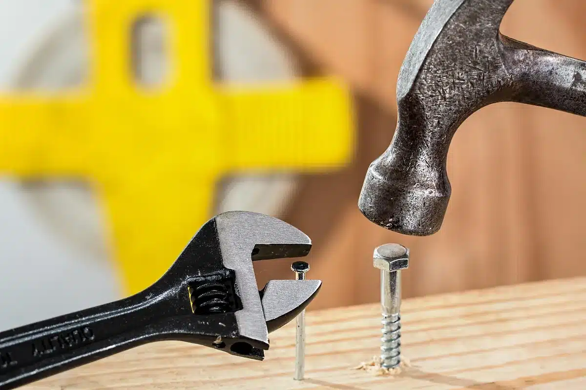 Collection of essential hand tools including hammer, drill, screws, and sandpaper for building a pallet bench