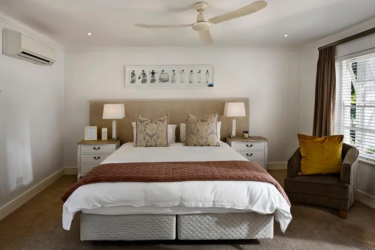 Person measuring wall space above bed with tape measure for headboard sizing