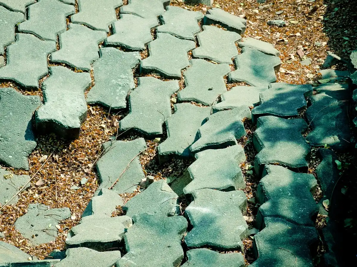 Close-up of interlocking pavers being laid on a prepared base in daylight