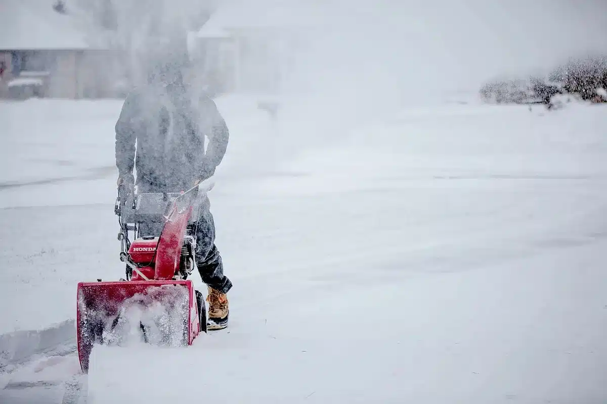 Leaf blower aimed at an exterior dryer vent during daytime