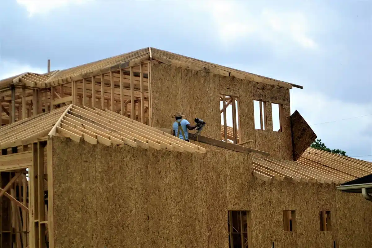 Carpenter fastening plywood panel with screws in a bright room