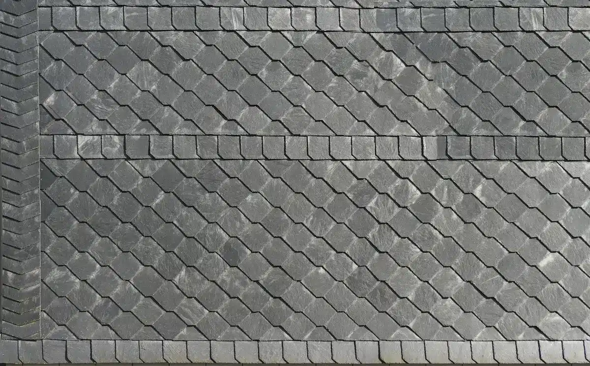 Hands holding roofing shingle and metal panel samples over lumber