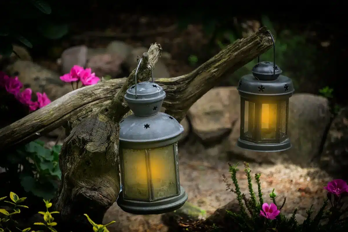 Glass lanterns hanging from a pergola and tree branches in bright daylight