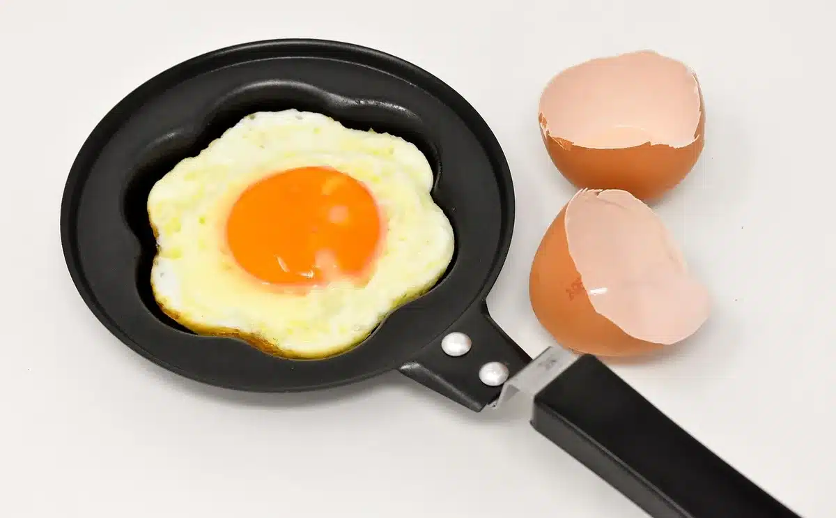 Hand holding a refrigerator magnet against the base of a frying pan