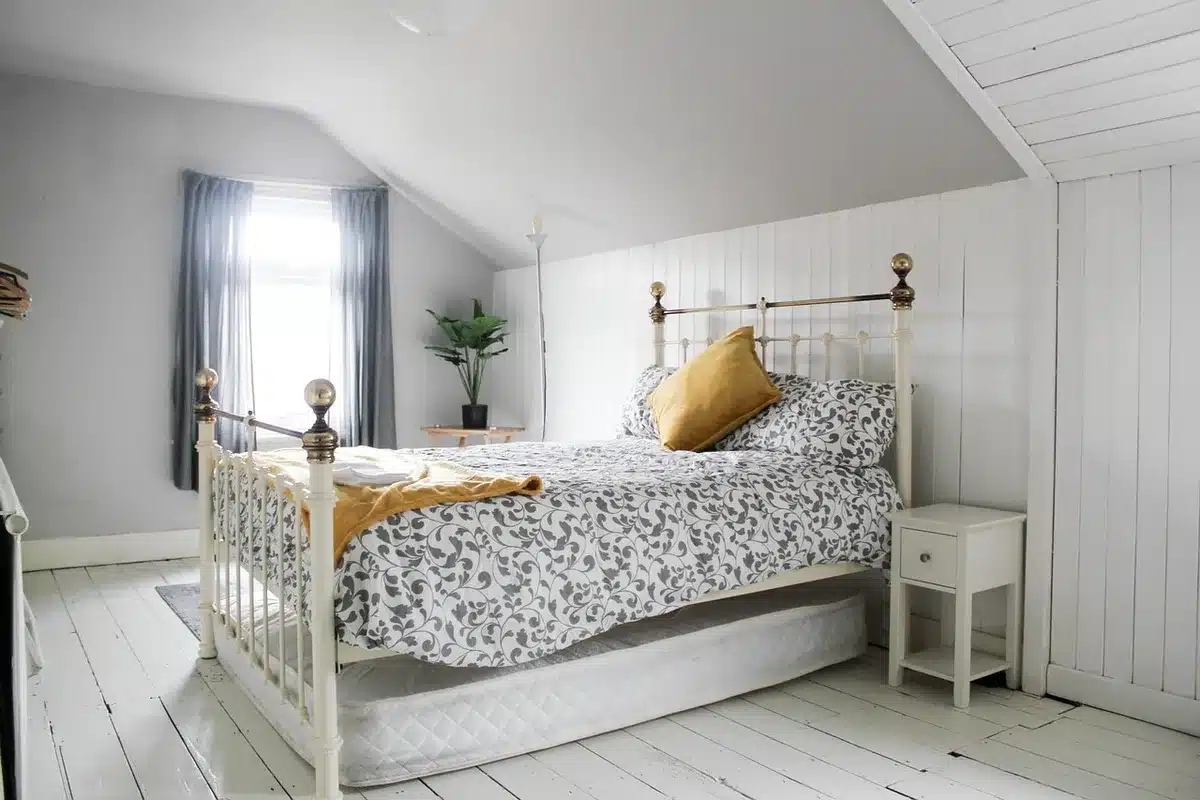 Bed with three pieces of driftwood mounted above the headboard on a blue-gray wall