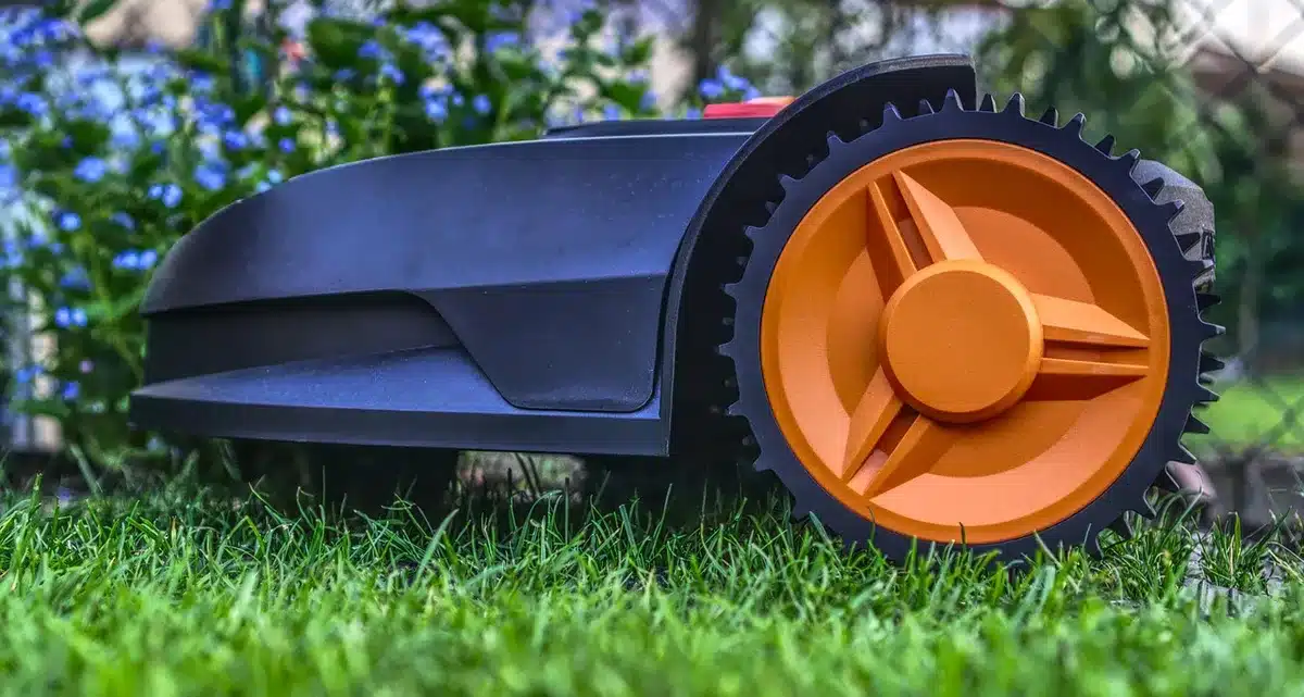 Container catching oil draining from a lawn mower drain plug in daylight
