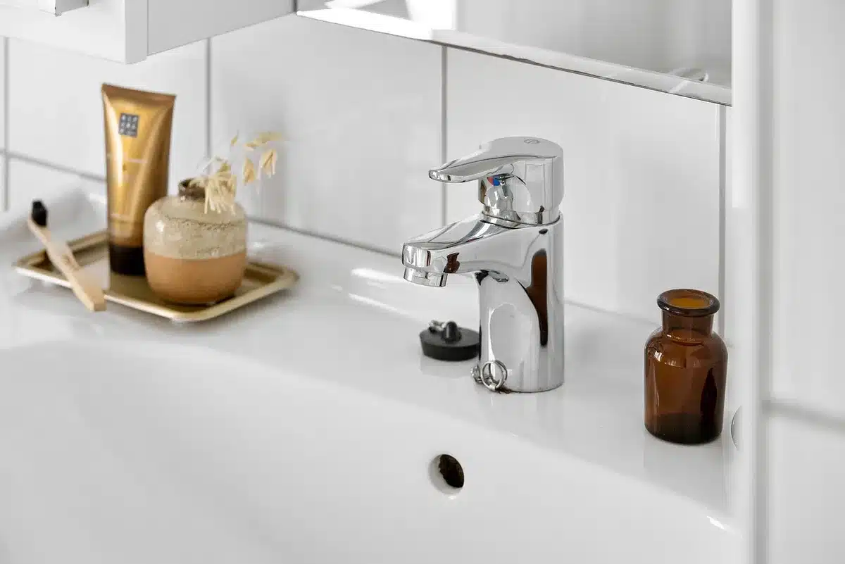 Hands using a level and drill to mount a paper towel holder under a cabinet