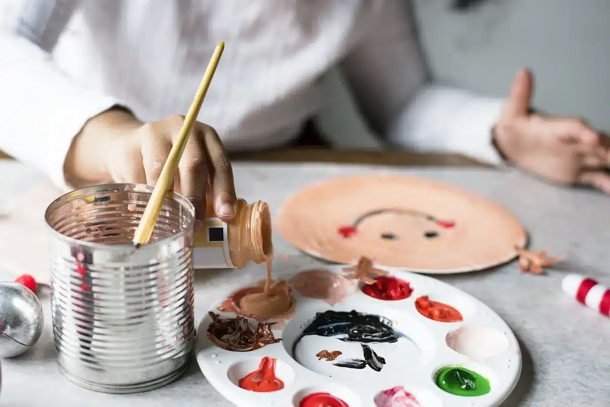 Table with paints, brushes, twine and a retired frying pan ready for upcycling
