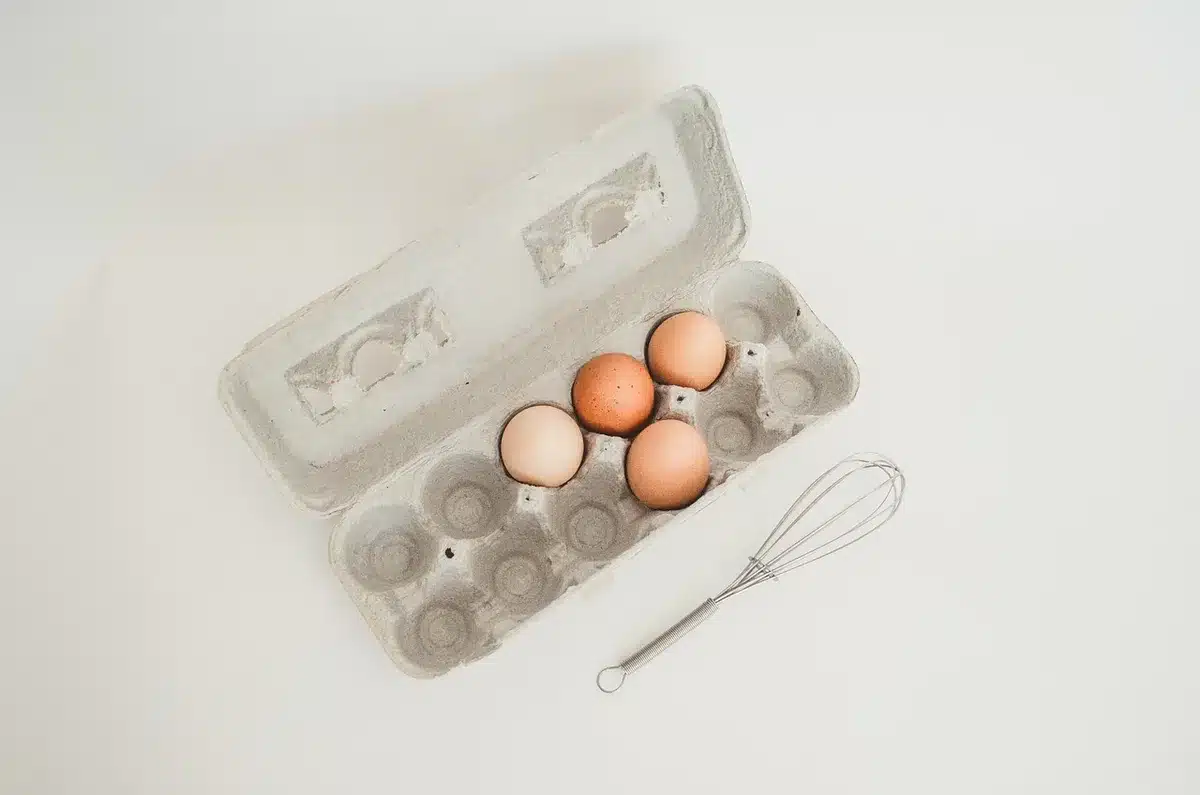 Open egg carton laid flat on a rolling cart shelf holding small craft items