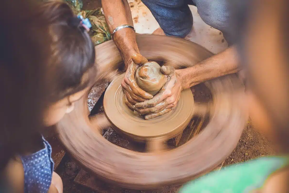 Hands shaping clay on parchment with rolling pin and cutter for a paper towel cover