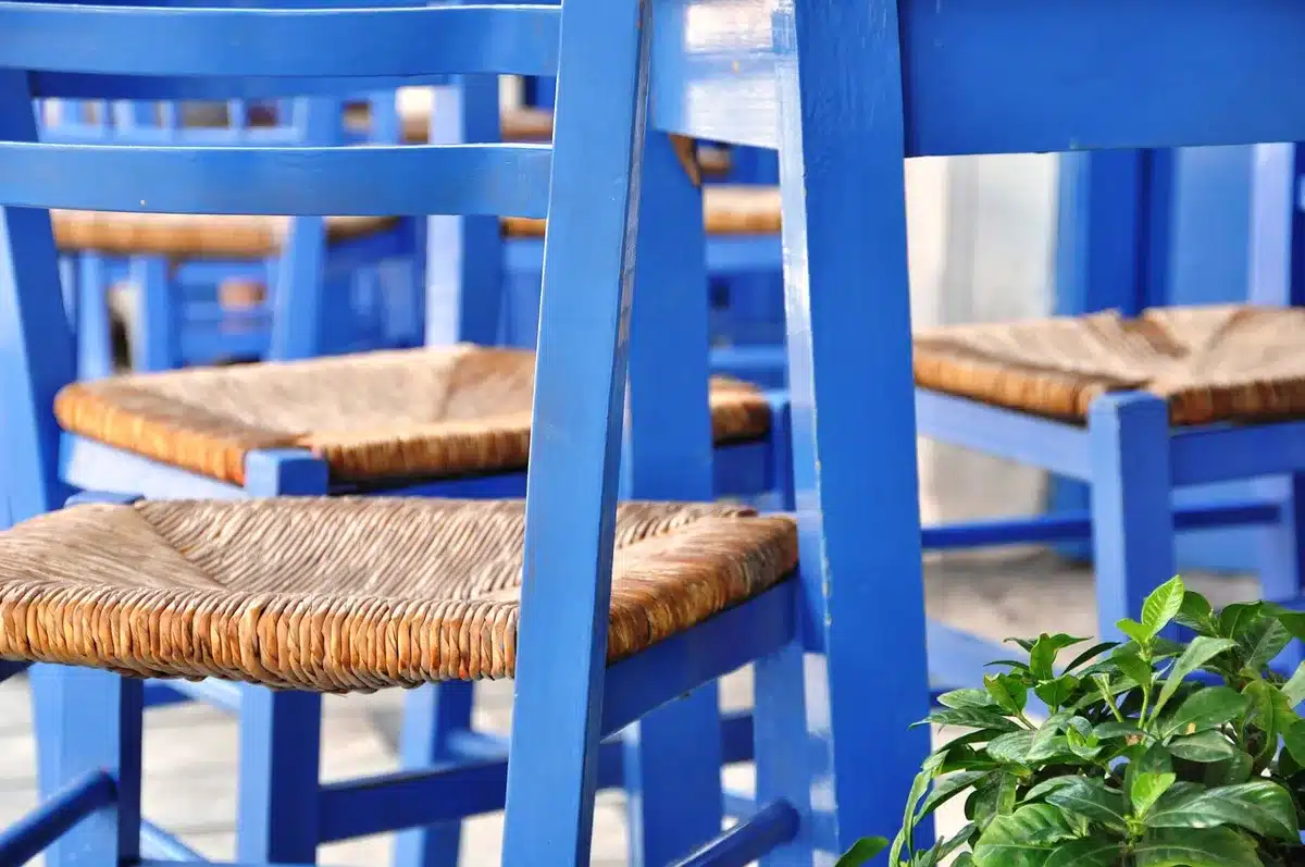 Two round wicker nesting tables on a sunny patio next to a rattan sofa
