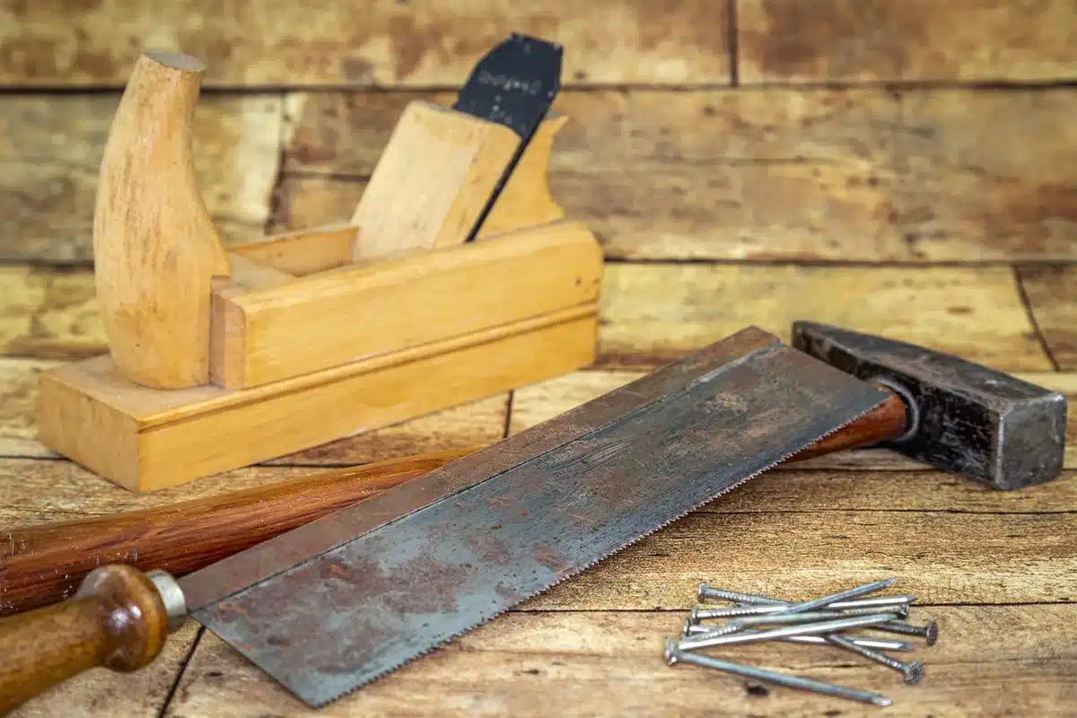 Sunlit porch with redwood boards and hands arranging them on a bright workbench