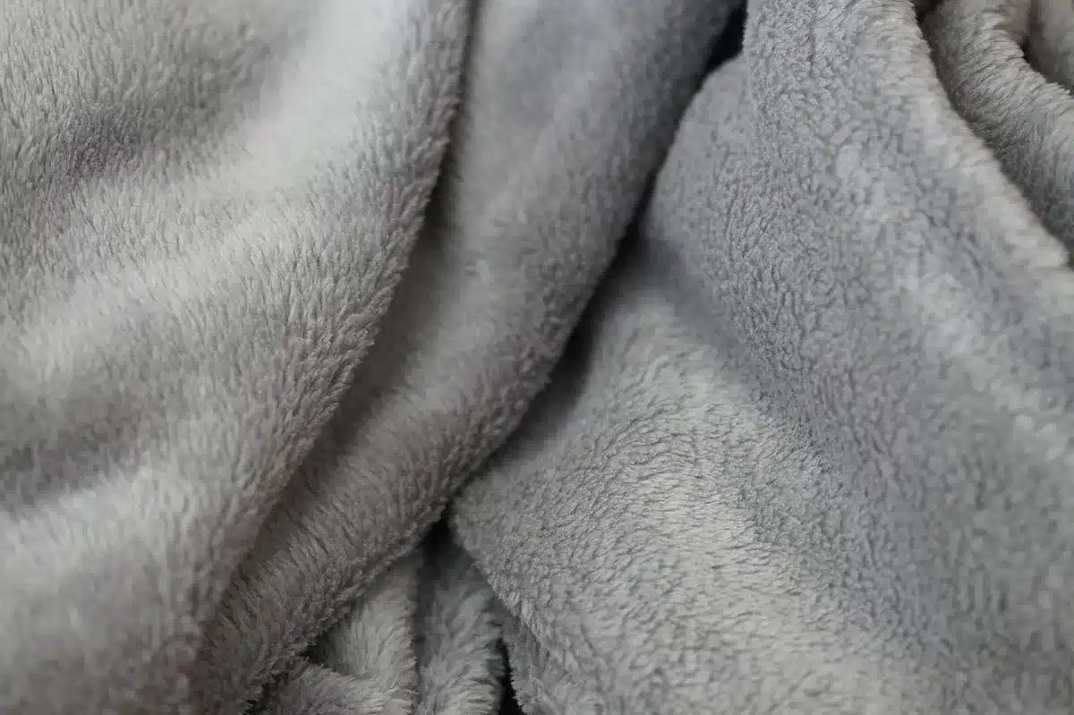 Microfiber cloth rubbing creamy cleaner on a painted cabinet edge to remove grease