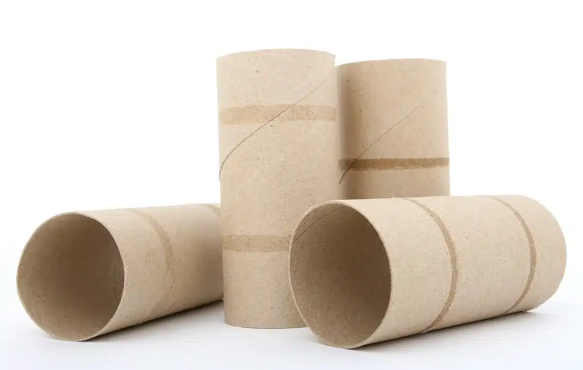 Craft table with empty toilet paper rolls, fabric scraps and scissors laid out