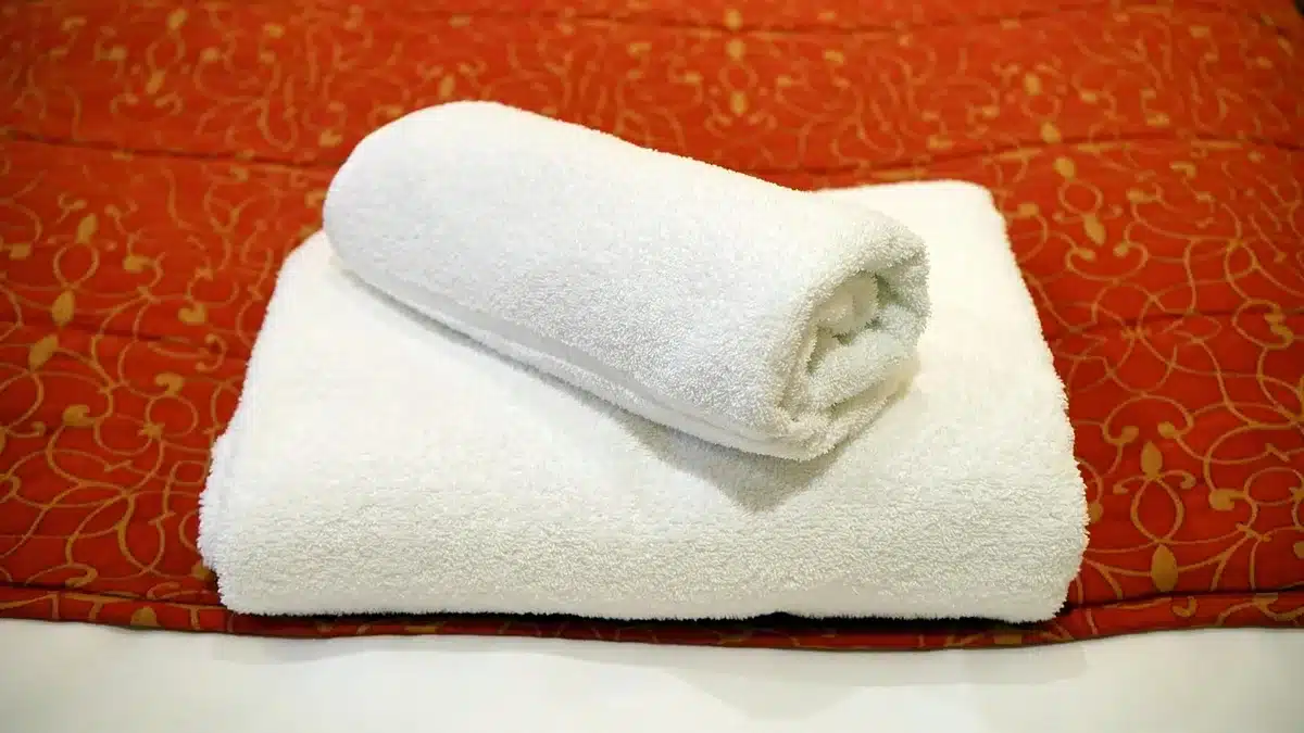 Close-up of a bamboo wall cradle holding a neatly rolled towel